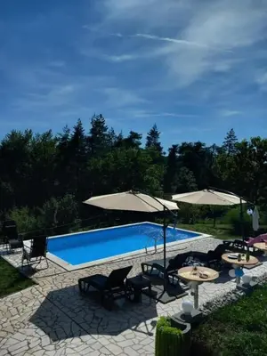 a swimming pool with umbrellas and chairs and tables at Vikendica Popovic in Doboj