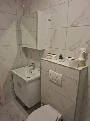 a white bathroom with a toilet and a sink at Apartman Idea 2 in Tuzla