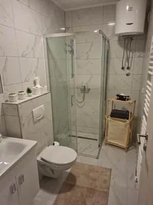 a white bathroom with a shower and a toilet at Apartman Idea 2 in Tuzla