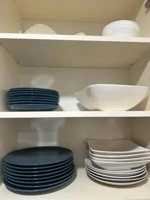 two shelves with plates and bowls in a pantry at Apartman Lagom in Banja Luka