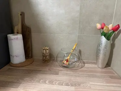 a shelf with a bowl of tulips and a vase of flowers at Apartman Lagom in Banja Luka