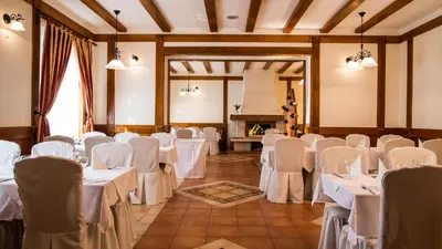 a room with white tables and chairs and a fireplace at Hotel Knez in Kupres