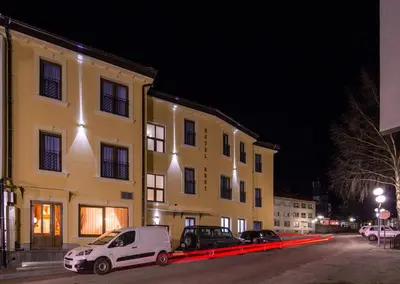 a white car parked in front of a yellow building at Hotel Knez in Kupres