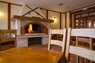a living room with a fireplace and a table and chairs at Hotel Knez in Kupres