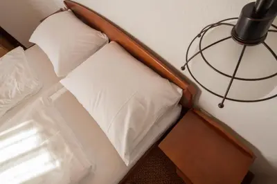 a small bed with white pillows and a lamp at Hotel Knez in Kupres