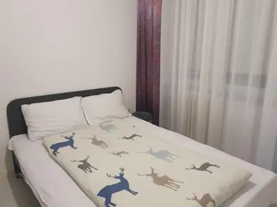 a bed with a comforter on top of it at Apartman Magelan in Bosanska Gradiška