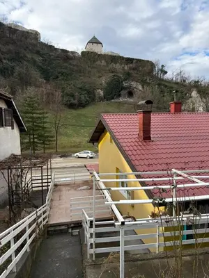 a yellow house with a red roof and a hill at Wooden house Tešanj in Tešanj