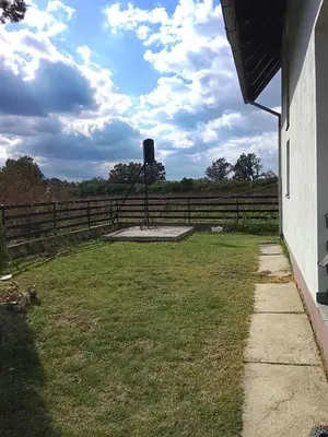 a fence with a tank in the middle of a yard at Vikendica Brvnička Oaza mir i priroda kraj Šamca