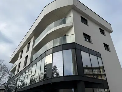 a tall white building with glass windows at Real Comfort in Bugojno