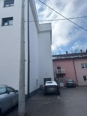 a white building with cars parked in a parking lot at Real Comfort in Bugojno