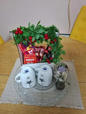 a table with a bouquet of christmas gifts and two mugs at Stan na dan Čaršija in Gračanica