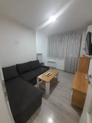 a living room with a black couch and a table at Jagoda stan na dan in Prijedor