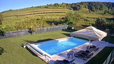 a swimming pool with an umbrella and some chairs at Arden House - Mountain Escape with Pool in Mali Radić