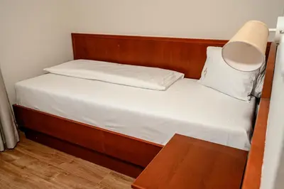 a small bed with a wooden headboard and white sheets at New Lake in Laktaši