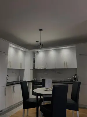 a kitchen with white cabinets and a table and chairs at Apartman Blagojević in Banja Luka
