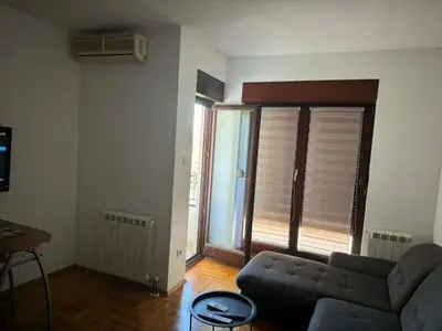 a living room with a couch and a large window at Trojka in Banja Luka