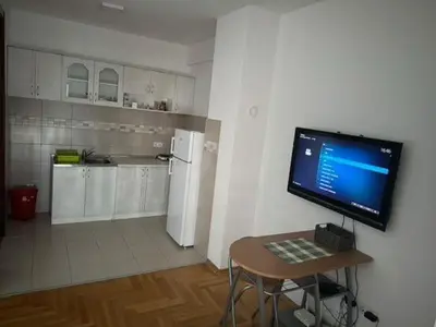 a kitchen with a table with a television on a wall at Trojka in Banja Luka