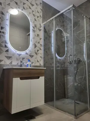 a bathroom with a shower with a sink and a mirror at Apartment Dora 3 in Banja Luka