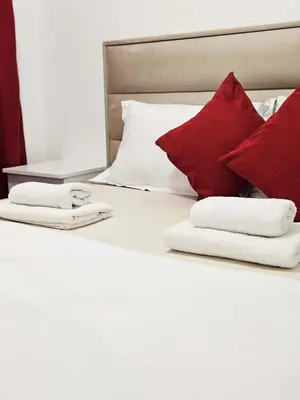 a bed with red pillows and towels on it at Apartment Dora 3 in Banja Luka