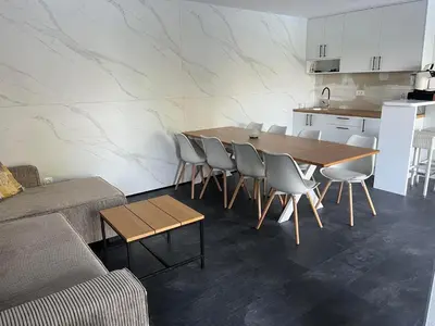 a dining room with a table and chairs and a kitchen at Šumska Duša in Banja Luka