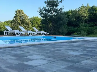 a swimming pool with white chairs next to at Šumska Duša in Banja Luka