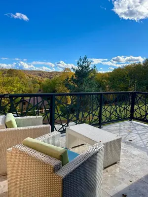 a patio with wicker chairs and tables on a balcony at Šumska Duša in Banja Luka