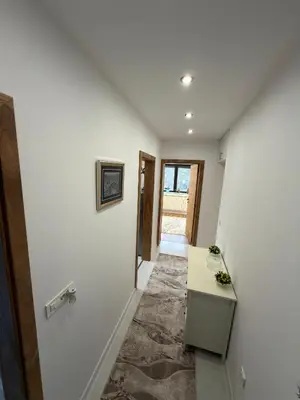 a hallway with a white wall and a table at Apartman Hendek Tuzla in Tuzla