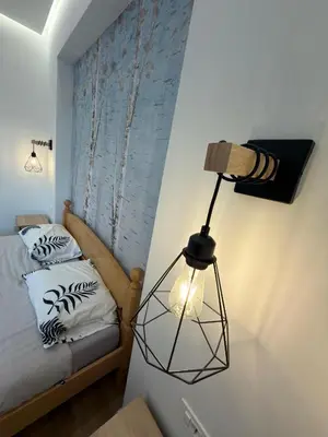 a small bedroom with a bed and a lamp at Apartman Hendek Tuzla in Tuzla