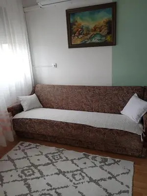 a couch in a living room with a painting on the wall at Retro-Apartman in Prijedor