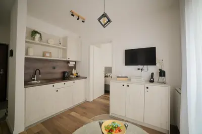 a kitchen with white cabinets and a flat screen tv at New City Nest - Tuzla Center in Tuzla