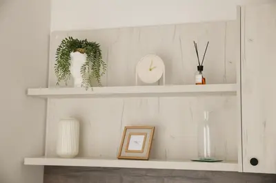 a white shelf with plants and a clock on it at New City Nest - Tuzla Center in Tuzla