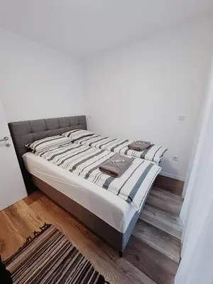 a bed sitting in a room with a wooden floor at New City Nest - Tuzla Center in Tuzla