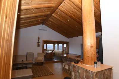 a living room with wooden ceilings and a stone pillar at Vikendica Ivanović in Banja Luka