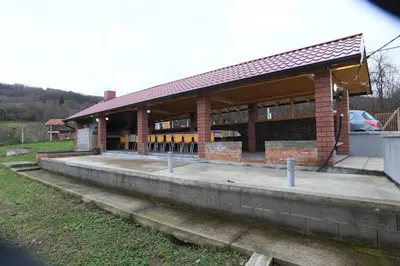 a brick building with a parking lot in front of it at Vikendica Ivanović in Banja Luka