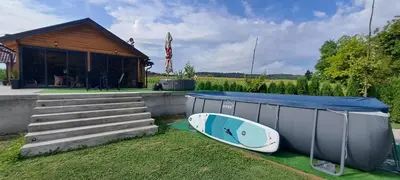 a house with a surfboard on the grass next to a building at Kuća za odmor River Nest