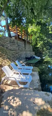 a group of white lounge chairs next to a river at Kuća za odmor River Nest