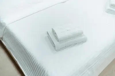 a white bed with two white towels on it at Apartman s garazom in Banja Luka
