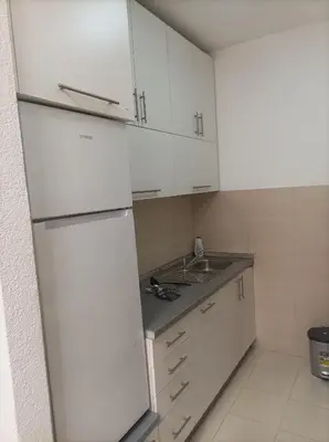 a white kitchen with a sink and a refrigerator at Apartman s garazom in Banja Luka
