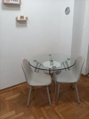 a glass table with two chairs and a vase on it at Apartman s garazom in Banja Luka