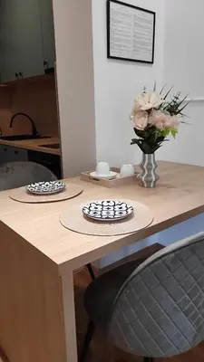 two plates on a wooden table with a vase of flowers at Apartman Lena 51 BL in Železnička Stanica Incel