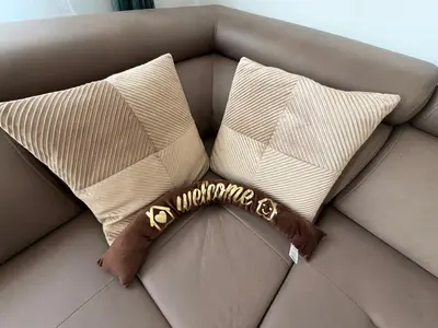 a brown scarf sitting on a couch with pillows at Urban Home Stupine in Ši Selo