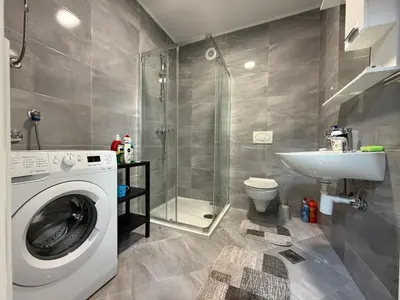 a bathroom with a washing machine and a sink at Urban Home Stupine in Ši Selo