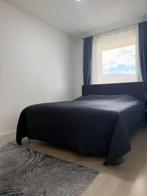 a bedroom with a bed with a window and a rug at Urban Home Stupine in Ši Selo