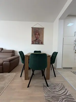 a dining room with a table and green chairs at Urban Home Stupine in Ši Selo
