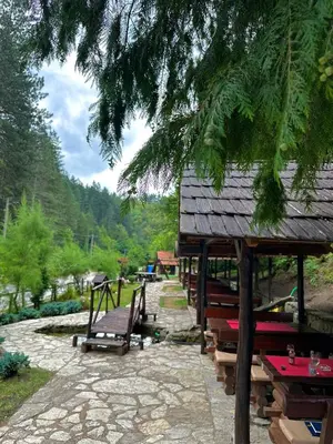 a building with wooden tables and benches in a park at Motel Stovrela in Cazin