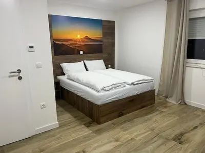 a bedroom with a bed with a painting on the wall at Apartmani Vidović in Prozor