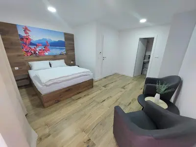 a small bedroom with a bed and a chair at Apartmani Vidović in Prozor
