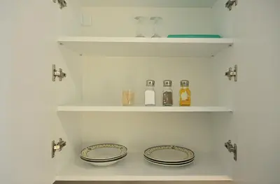 two plates and bottles on shelves in a kitchen at Apartman Nika in Banja Luka