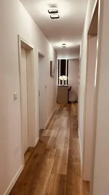 a hallway with white walls and wooden flooring at Premium Skver Tuzla - City Center in Tuzla