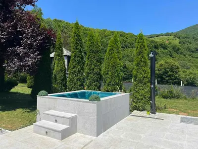 a hot tub in a garden with a hedge at Residence Green Pool & SPA in Visoko